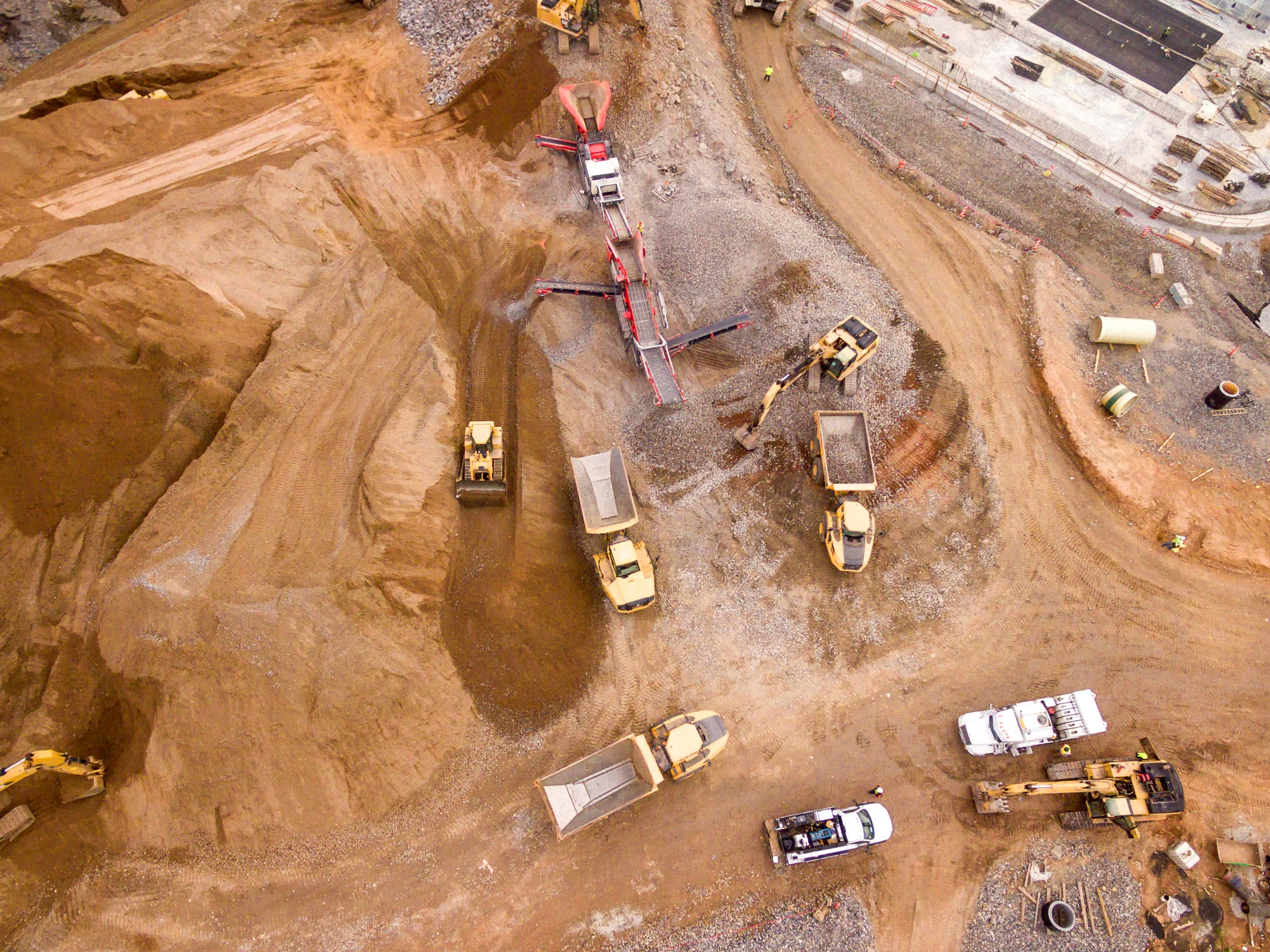 Top-down aerial view of an excavation site with haul trucks and loaders