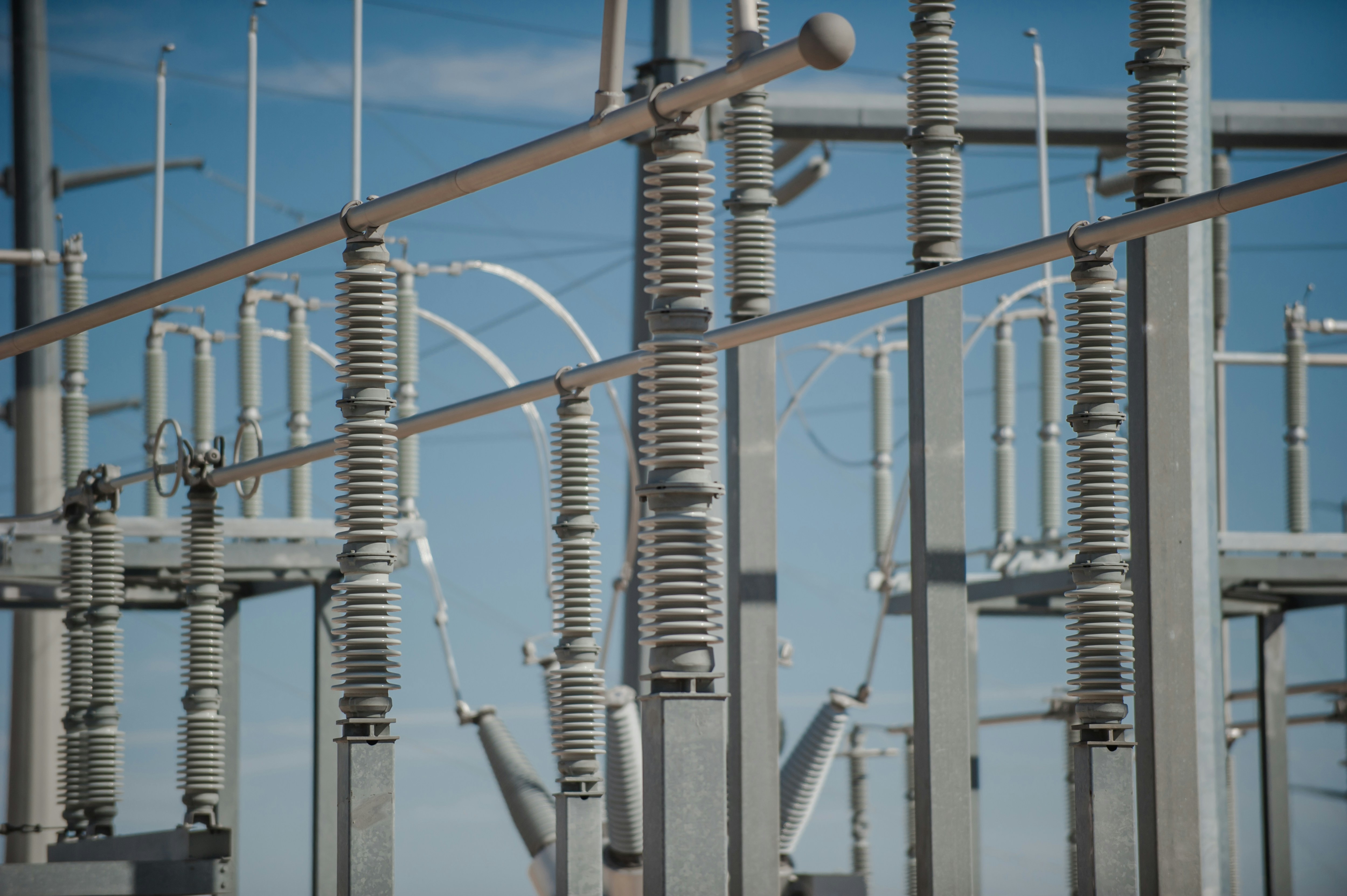 An electrical substation with insulators and busbars against a blue sky